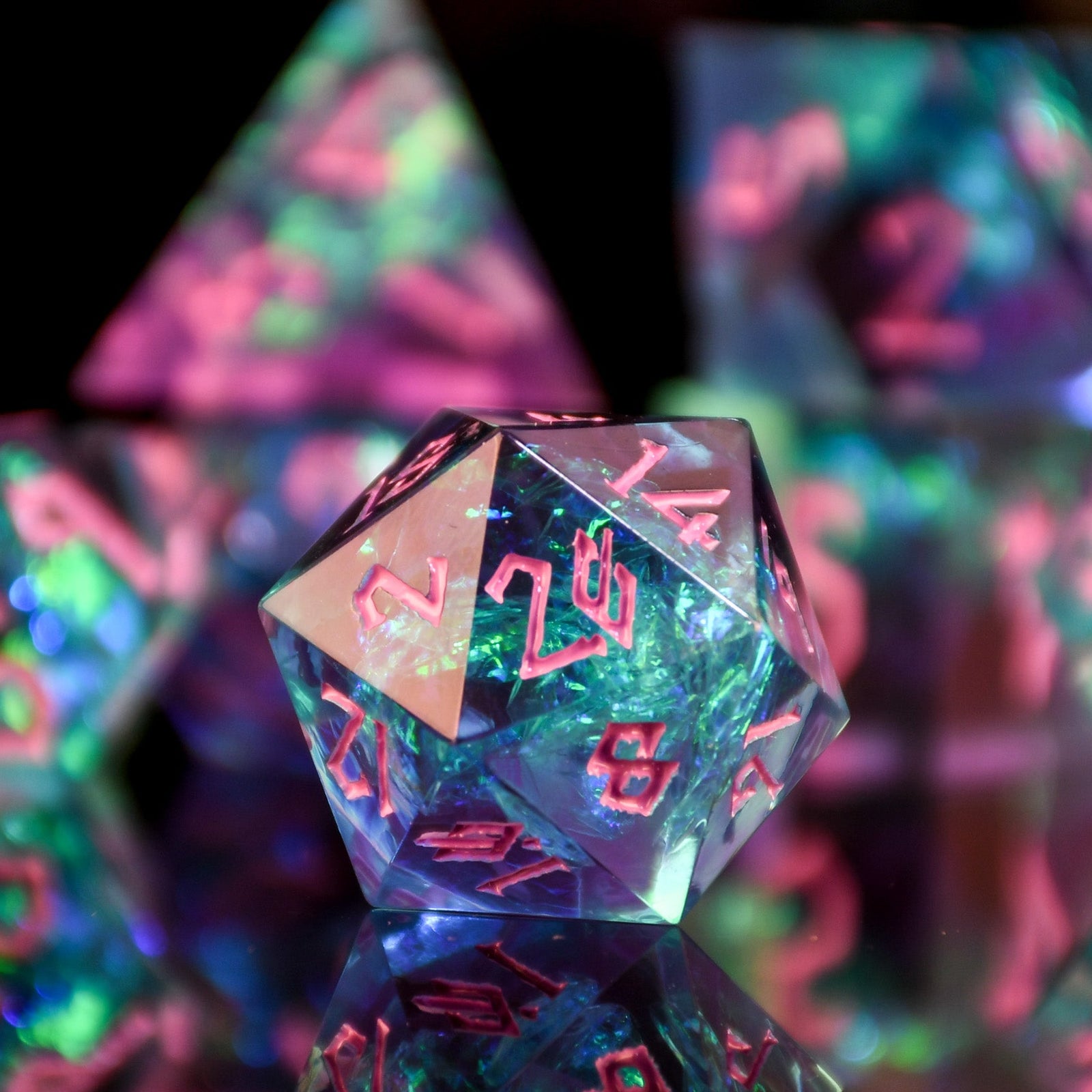A set of sharp-edged, multicolored resin dnd dice with pink hand-painted numbers, reflecting a vibrant blue, green and purple glow.