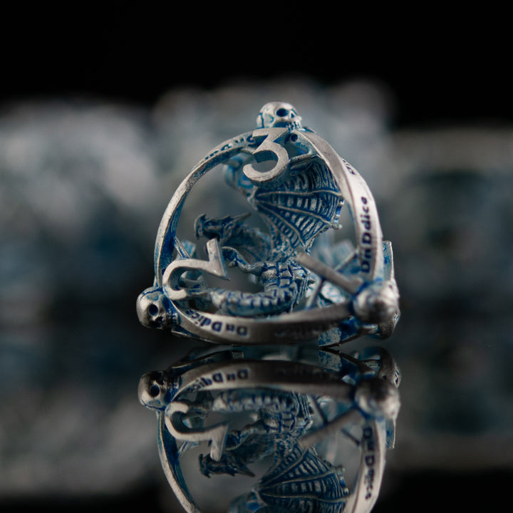 A set of hollow metal dice in silver and blue, displayed on a reflective surface.