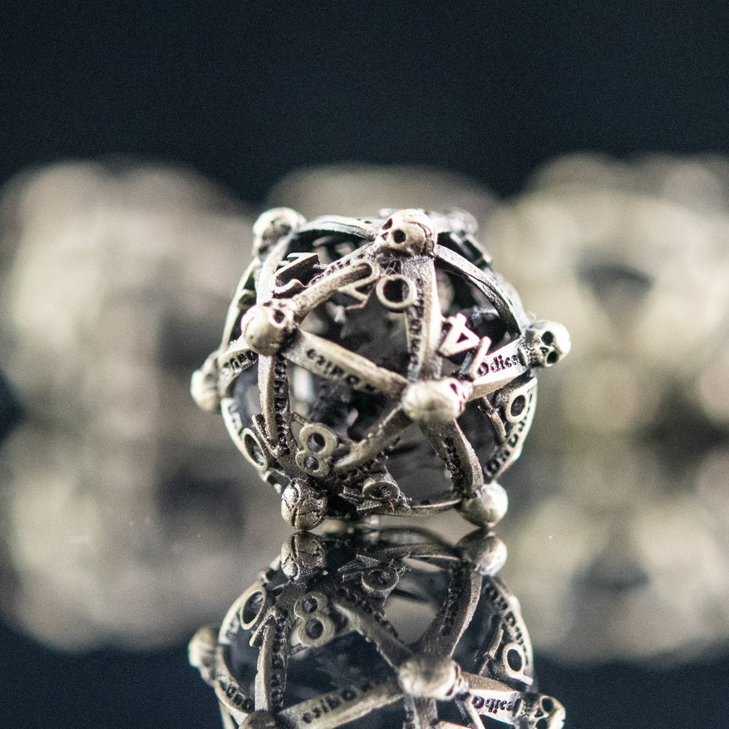 A set of embossed hollow metal dice in champagne gold color, displayed on a reflective surface.