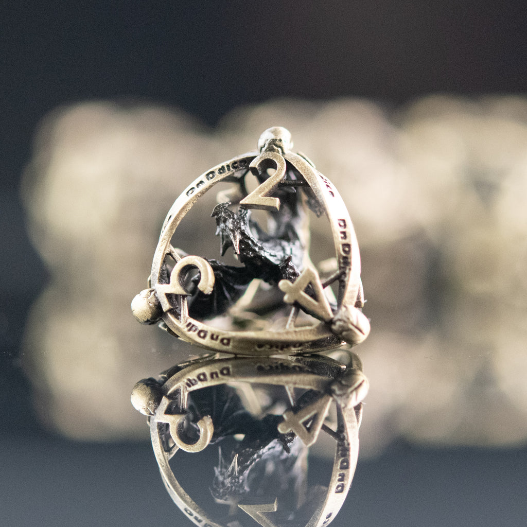 A set of embossed hollow metal dice in champagne gold color, displayed on a reflective surface.