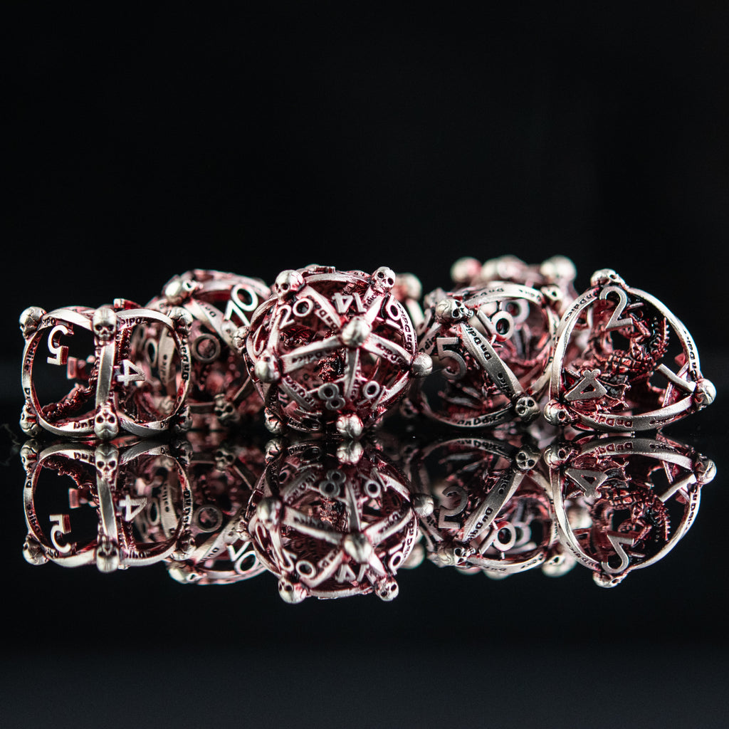 A set of embossed red and silver metal dice with intricate patterns on them, displayed on a reflective surface.