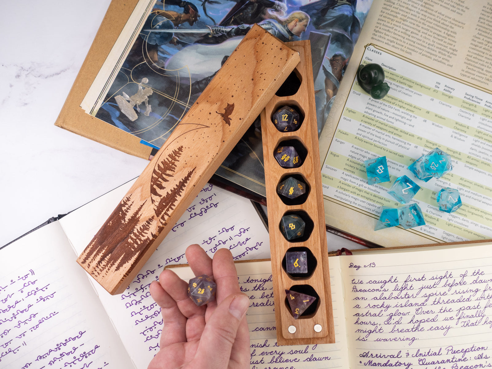 Wooden dice holder with engraved design on a table with books and papers.