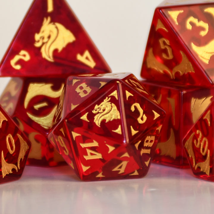 Set of red and gold polyhedral dice with dragon design on a dark background