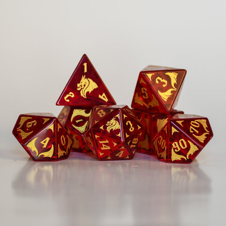 Set of red and gold polyhedral dice with dragon design on a dark background