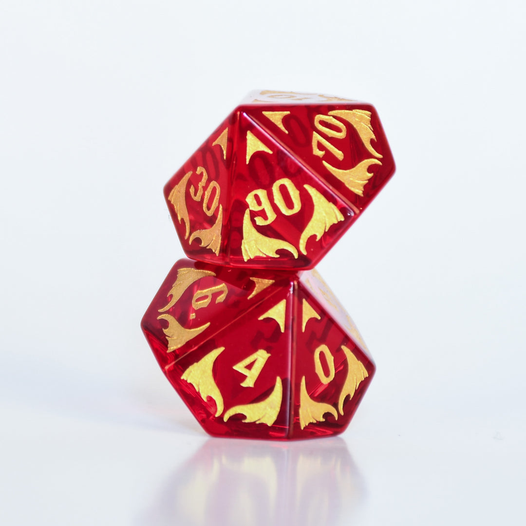 Set of red and gold polyhedral dice with dragon design on a dark background