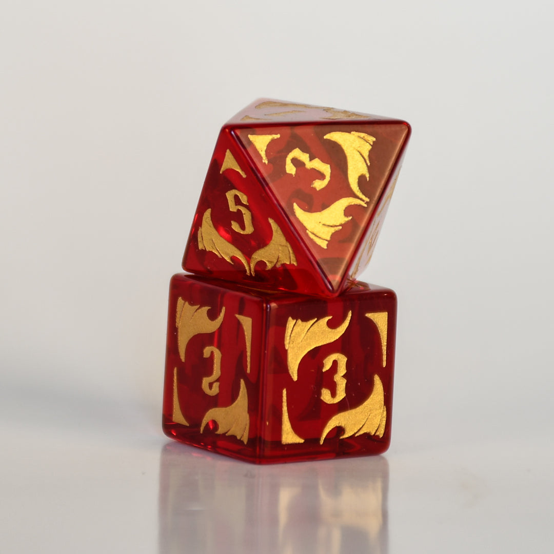 Set of red and gold polyhedral dice with dragon design on a dark background