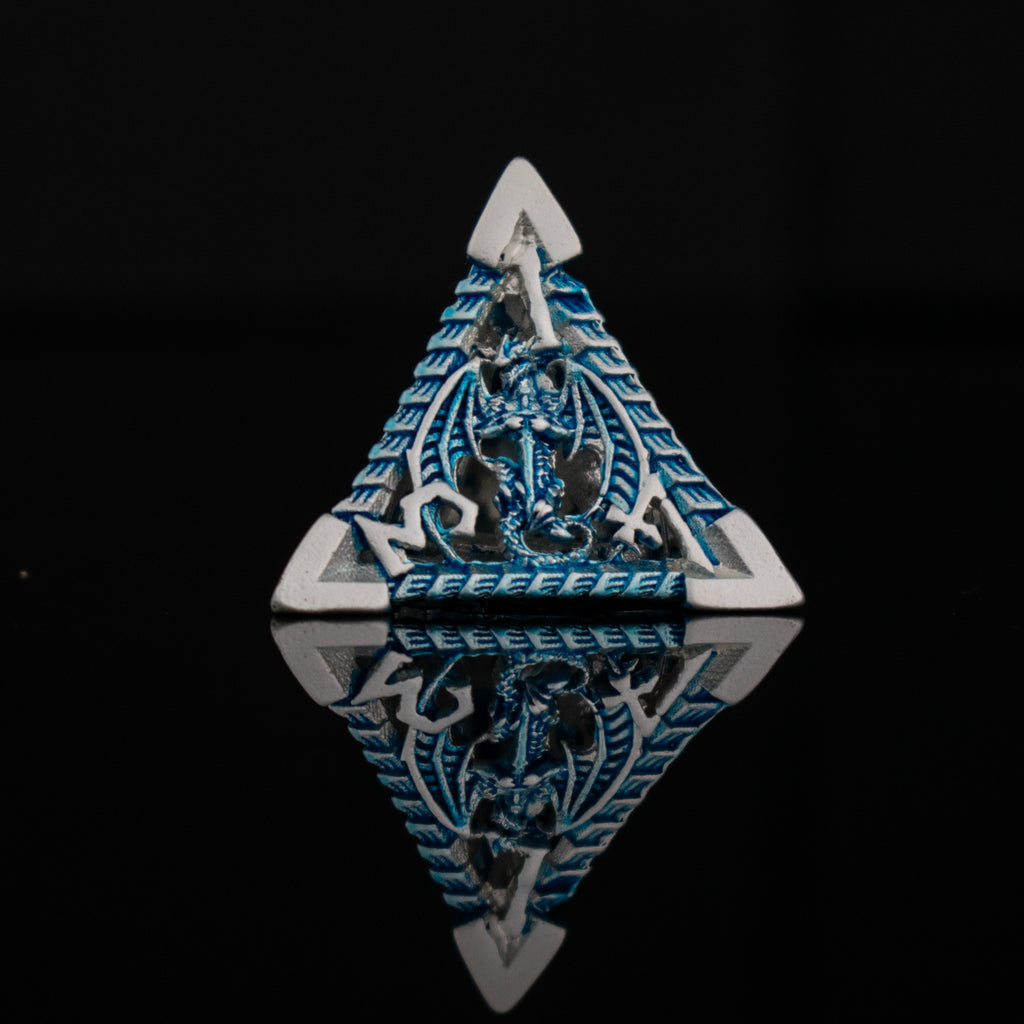 A set of embossed metal hollow dice in silver and blue, with dragons displayed on a reflective surface.