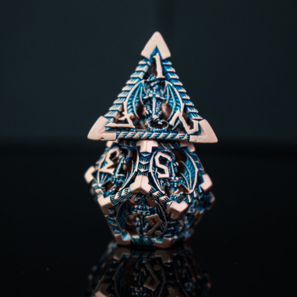 A set of embossed metal hollow dice in cobalt and bronze colors, displayed on a reflective surface.