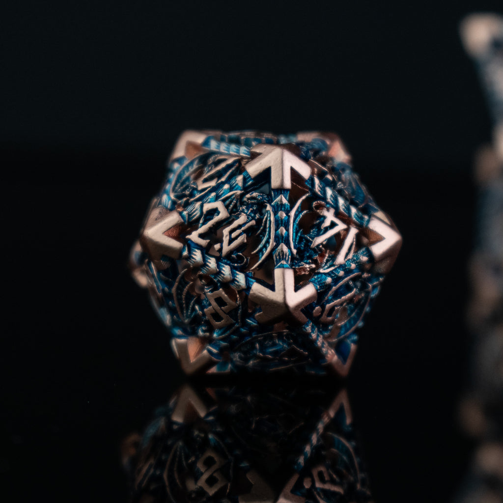 A set of embossed metal hollow dice in cobalt and bronze colors, displayed on a reflective surface.