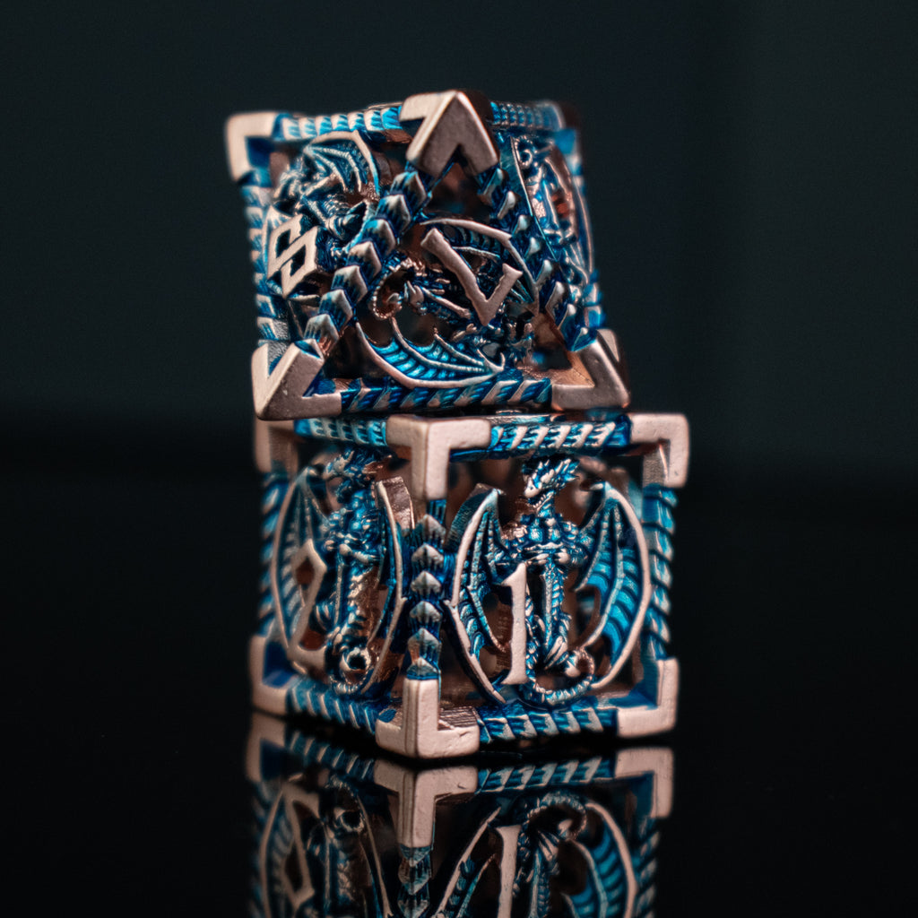 A set of embossed metal hollow dice in cobalt and bronze colors, displayed on a reflective surface.