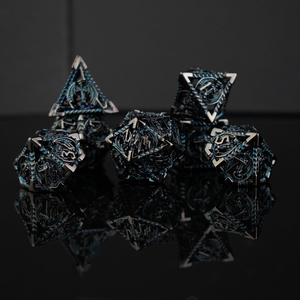 A set of embossed metal hollow dice in silver and blue colors, displayed on a reflective surface.