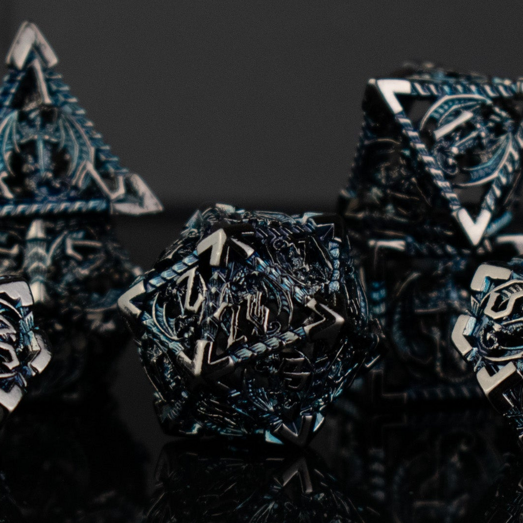 A set of embossed metal hollow dice in silver and blue colors, displayed on a reflective surface.