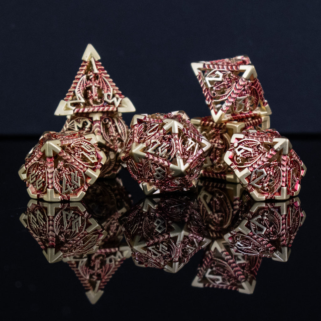 A set of embossed metal hollow dice in gold and red, with dragons displayed on a reflective surface.