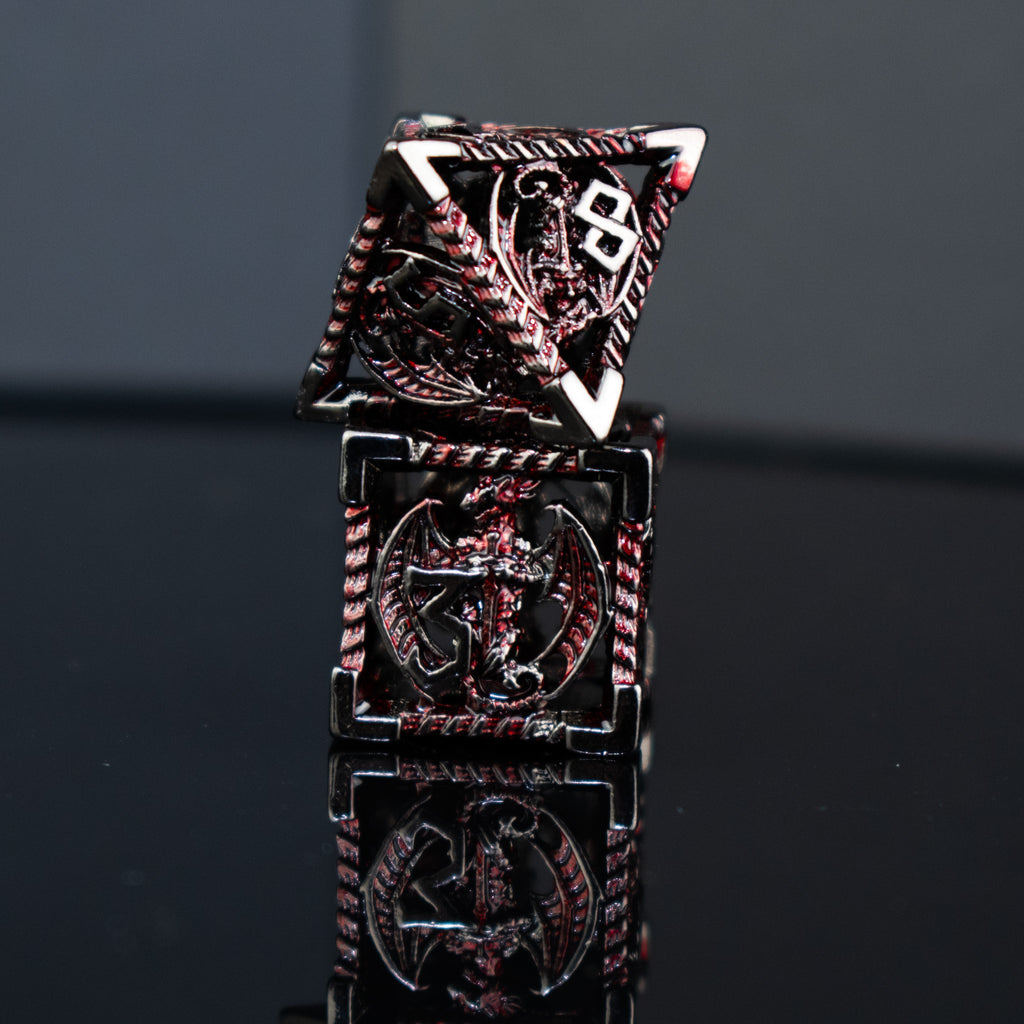 A set of embossed metal hollow dice in crimson and shadow colors, including various shapes such as a d4, d6, d8, d10, d12, and d20, displayed on a reflective surface.