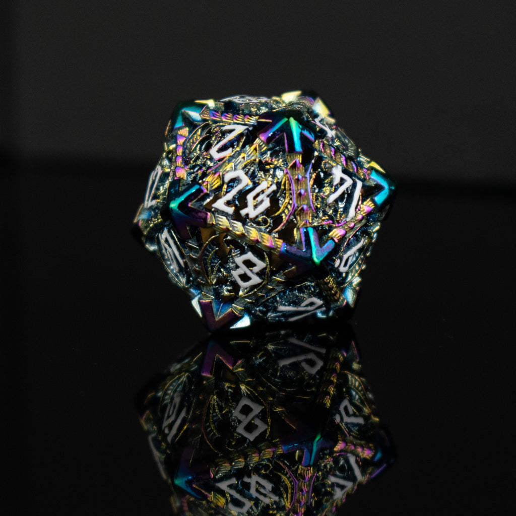A set of embossed metal hollow dice with iridescent colors reflecting light, placed on a dark reflective surface.
