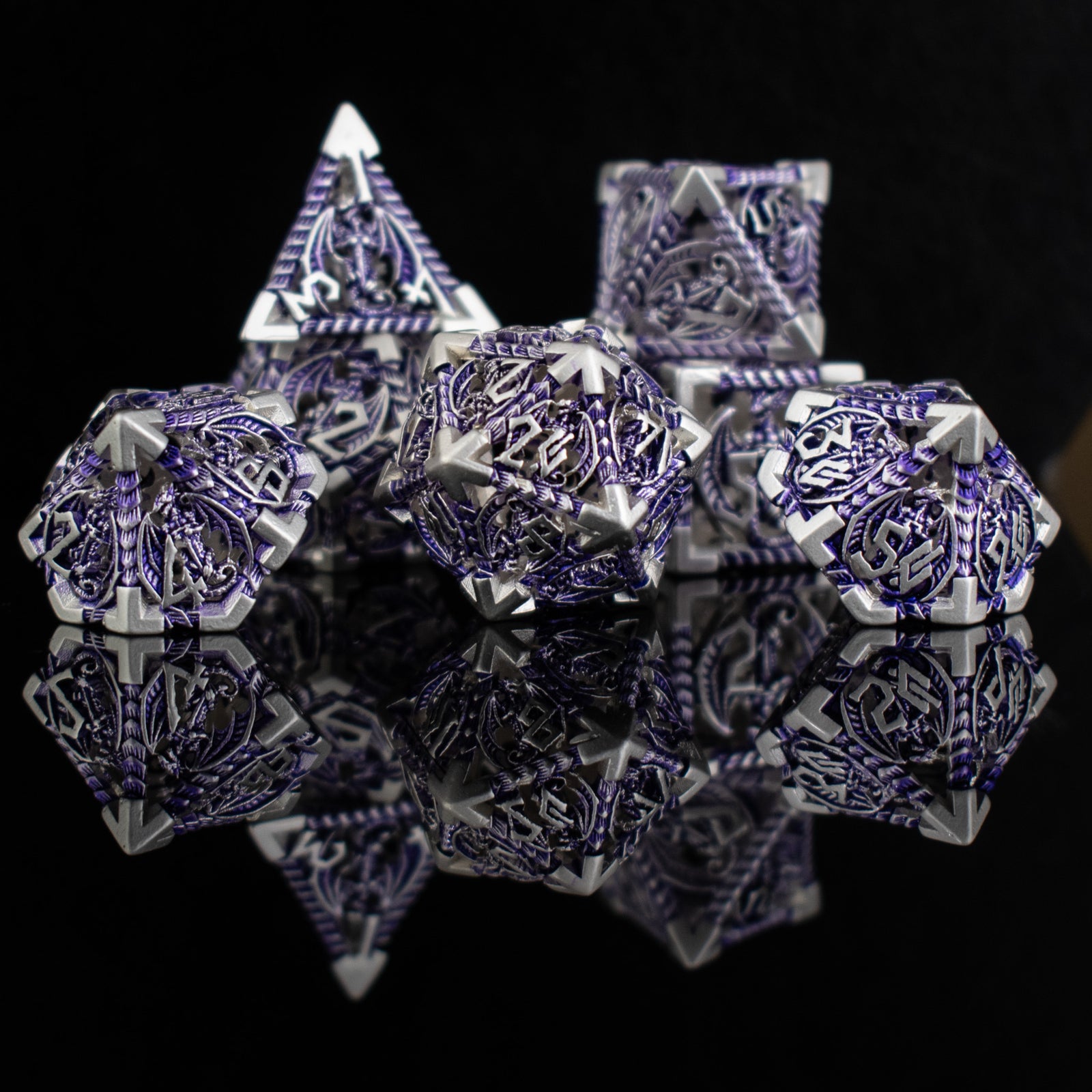 A set of embossed metal hollow dice in purple and silver, displayed on a reflective surface.