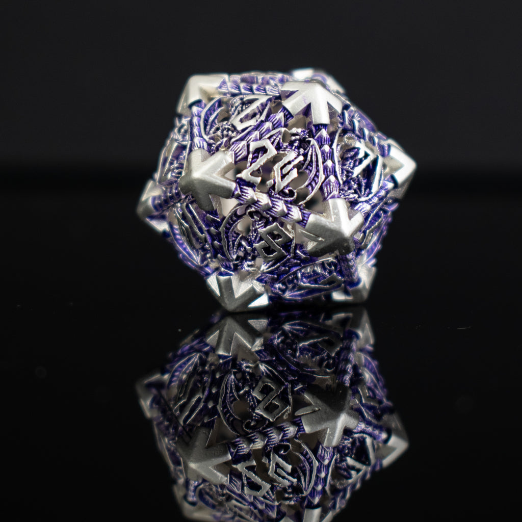 A set of embossed metal hollow dice in purple and silver, displayed on a reflective surface.