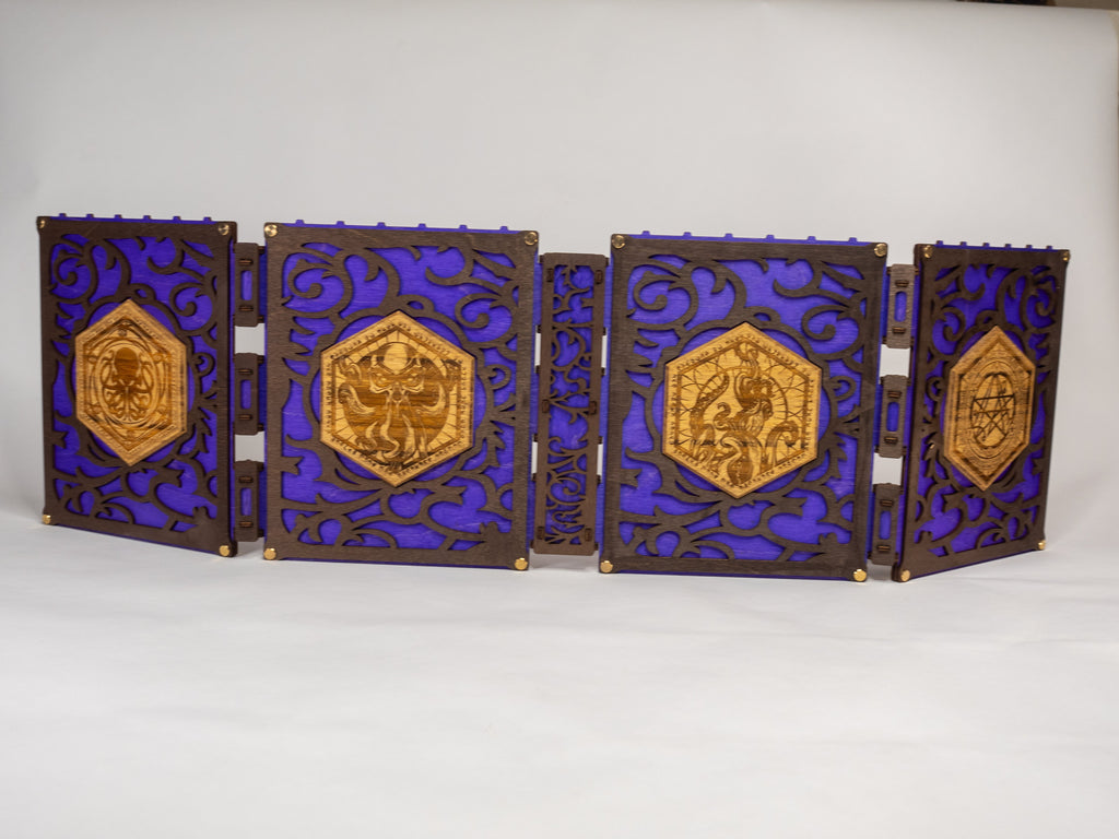 A selection of four compact dungeon master screens in various colors, each featuring a filigree pattern and brass fixtures, with magnetic acrylic panels for displaying maps and notes.