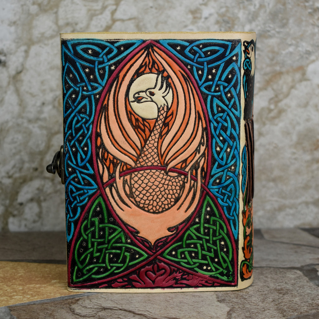 A hand-bound leather adventure journal with a full-grain goat leather cover featuring a Celtic inspired painted eagle design in brown, blue, and green.