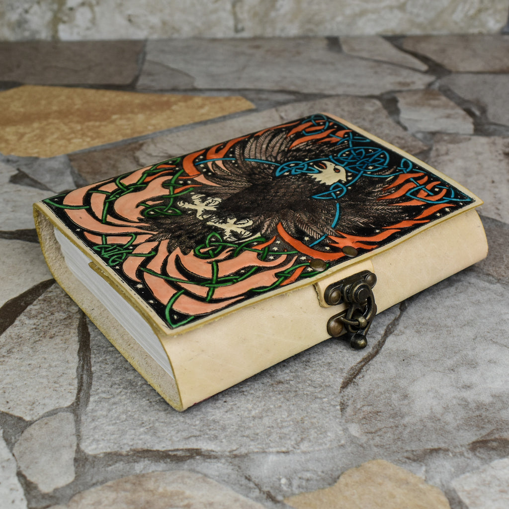 A hand-bound leather adventure journal with a full-grain goat leather cover featuring a Celtic inspired painted eagle design in brown, blue, and green.
