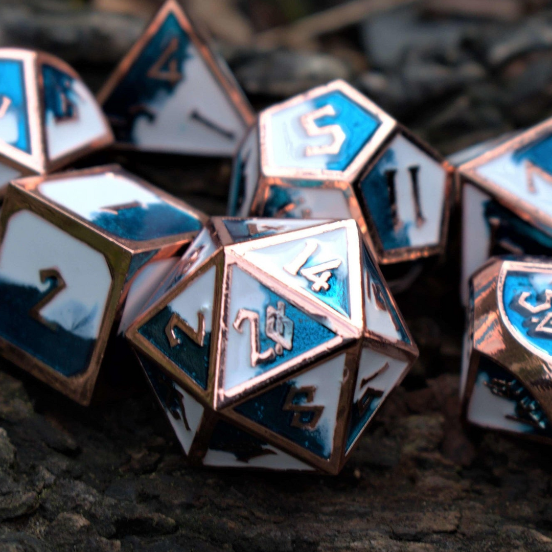 A set of metal dice with embossed numbers, featuring white faces with blue and silver details, scattered on a wooden surface.