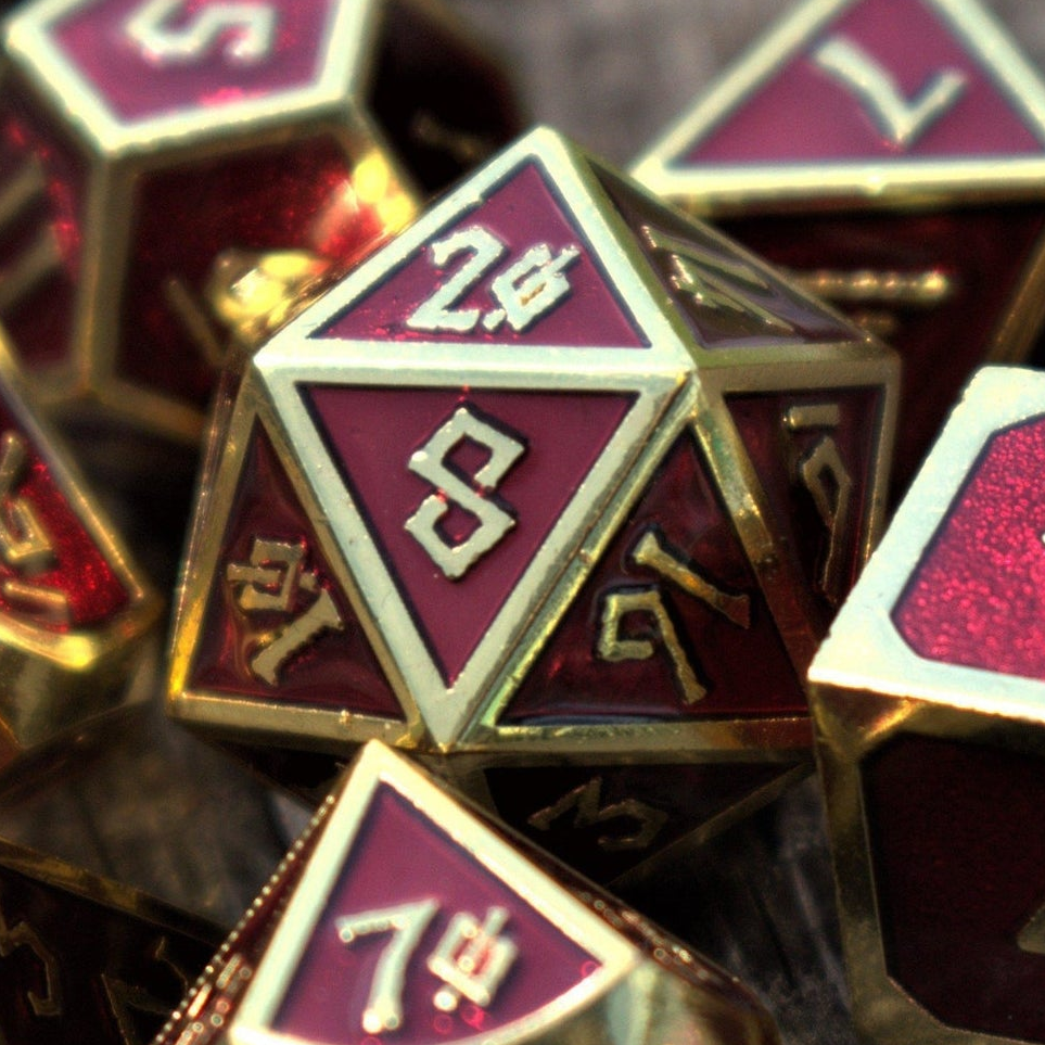 A set of deep royal red metal dnd dice with gold edges and borders, and gold numbering in a nordic font for wargaming tabletop gaming and board games
