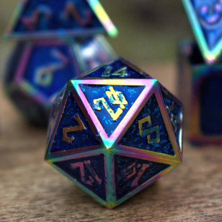 A set of metal dice with blue iridescent glitter coating and embossed golden numbers, displayed on a wooden surface.
