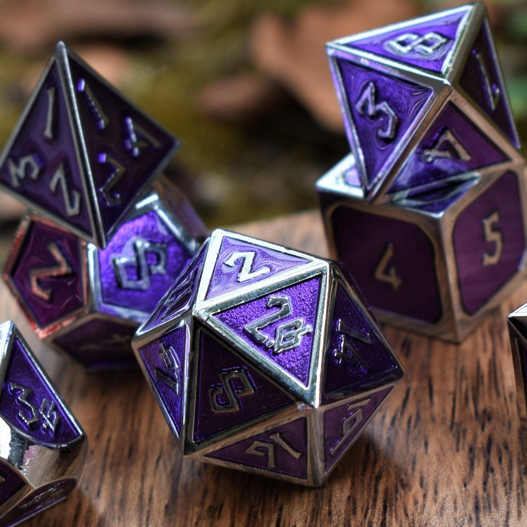 A set of purple and silver metal dice with embossed numbers, including various shapes typical for role-playing games.