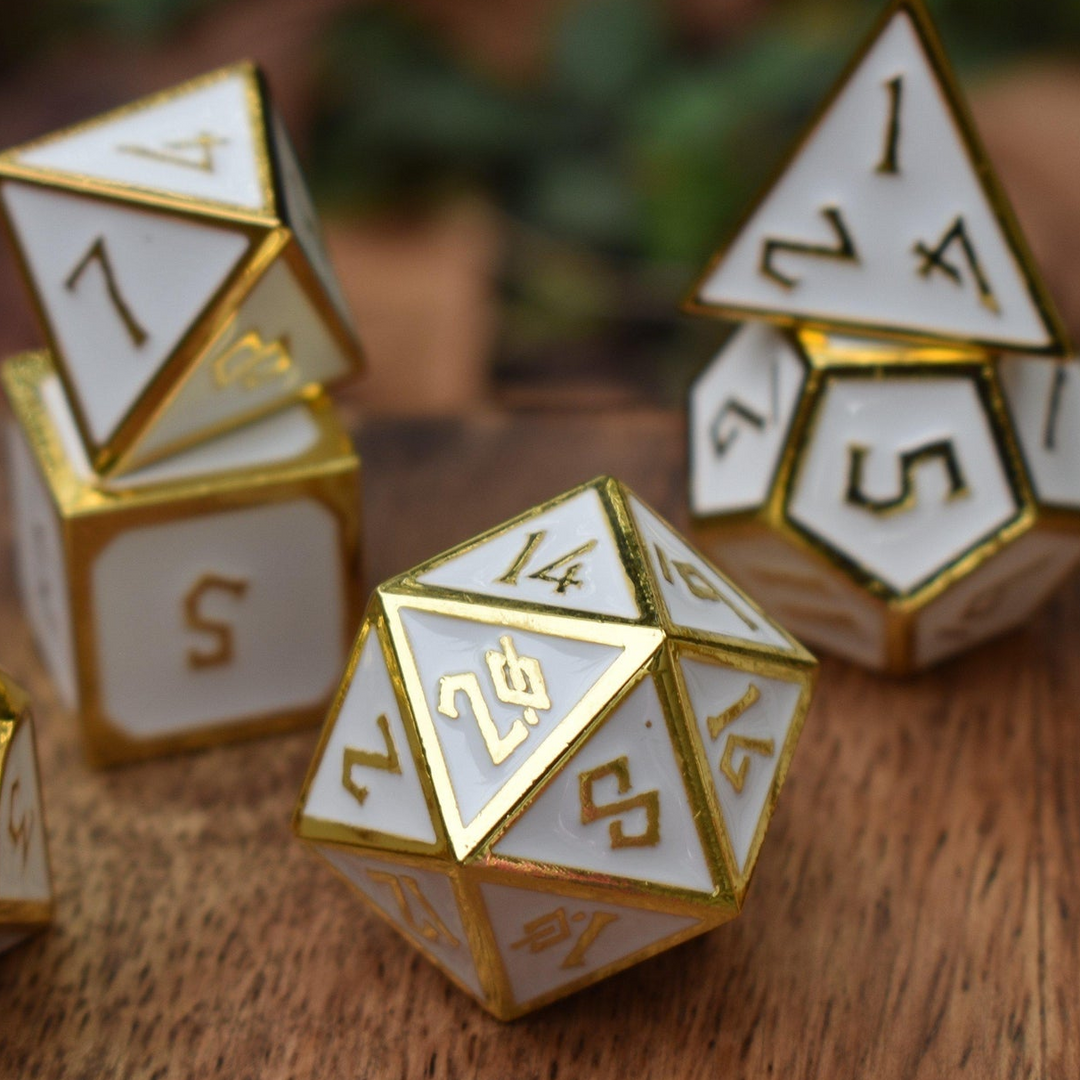 A set of white metal dnd dice with gold borders and numbers for tabletop gaming wargaming and board games