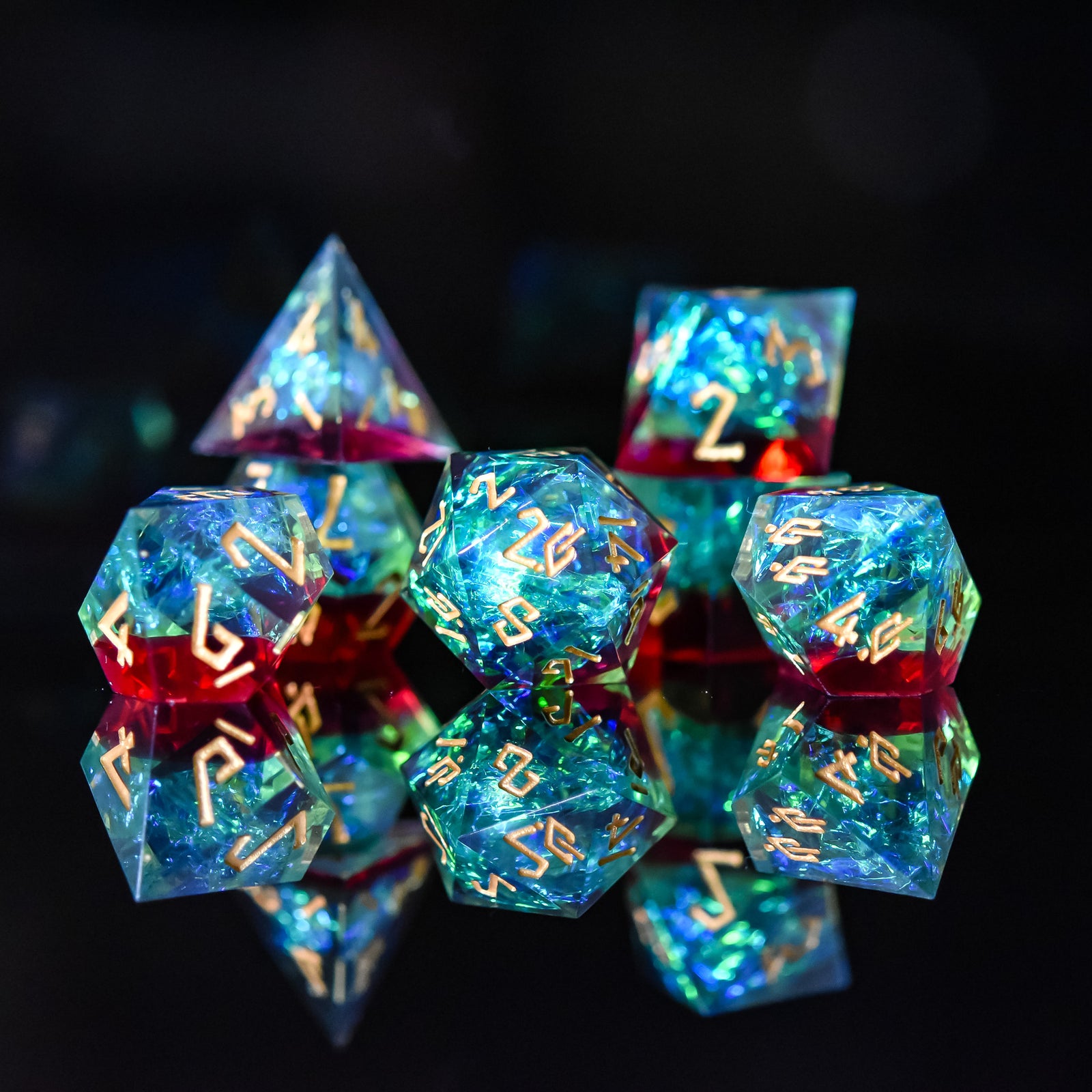 A set of sharp-edged resin dice with engraved numbers, featuring blue, green, and red colors, displayed on a reflective surface.