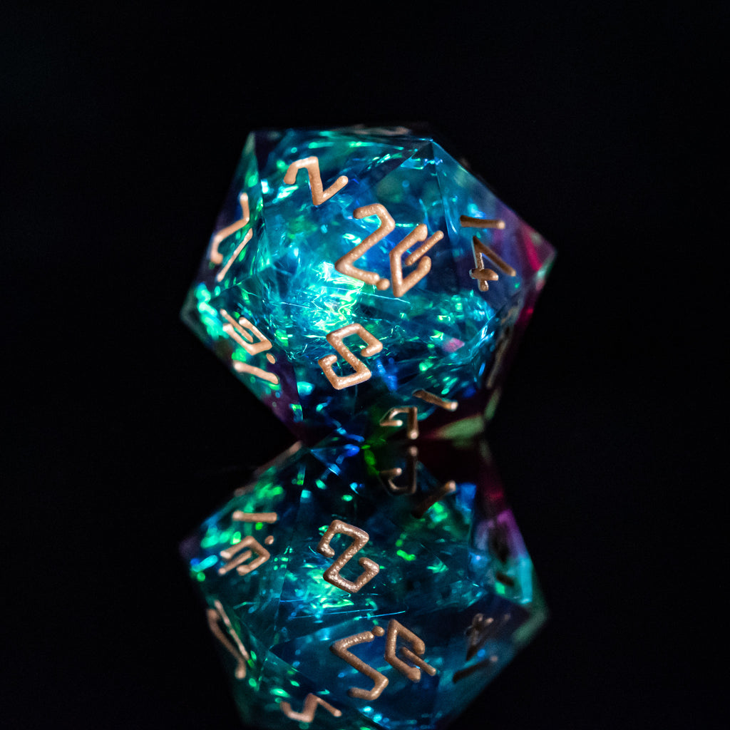 A set of sharp-edged resin dice with engraved numbers, featuring blue, green, and red colors, displayed on a reflective surface.