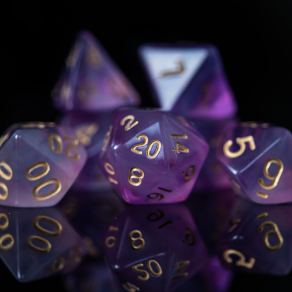 A set of purple acrylic dice with engraved gold numbers, commonly used for role-playing games.