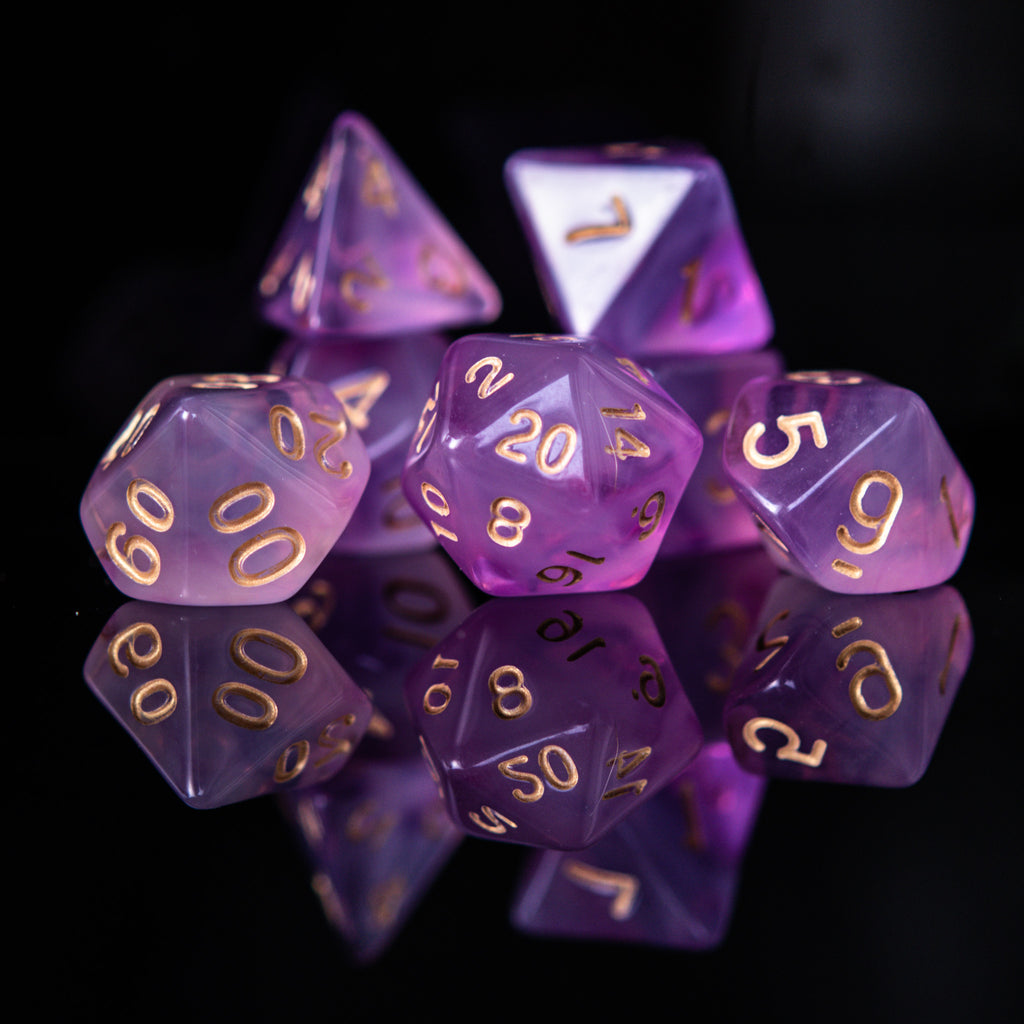 A set of purple acrylic dice with engraved gold numbers, commonly used for role-playing games.
