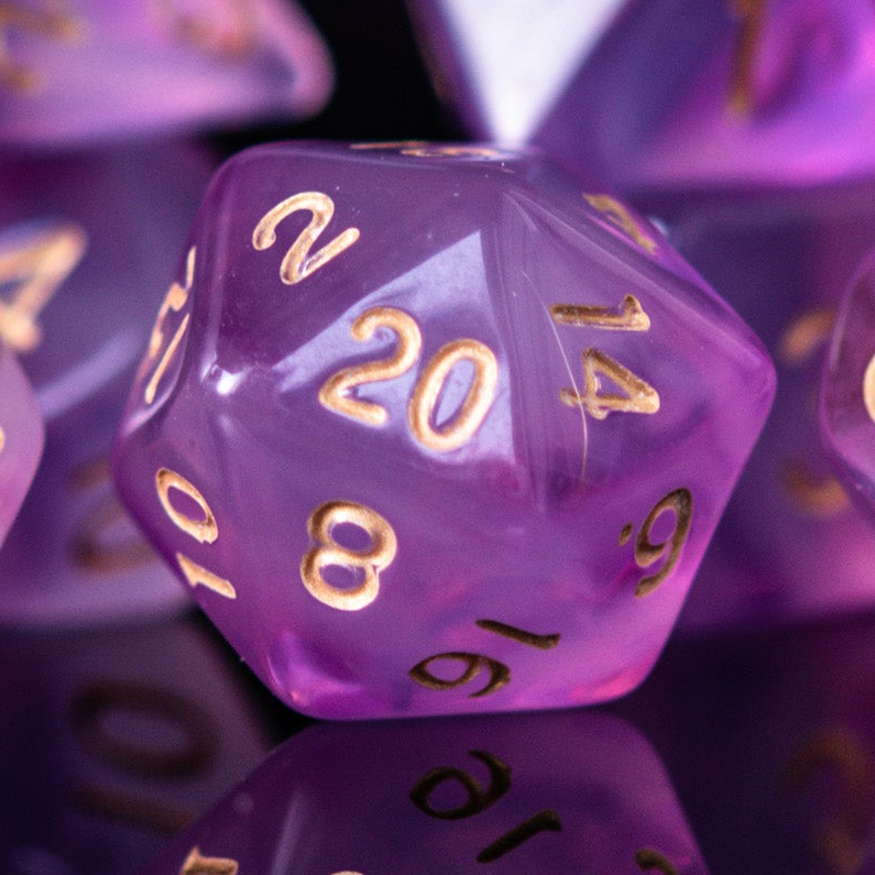 Purple polyhedral dice with gold numbers on a reflective surface
