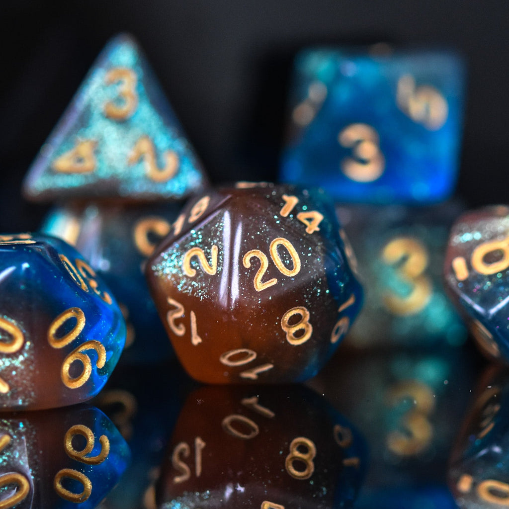 A set of acrylic dice featuring a mix of shimmering blue and orange colors with gold simple numbering for playing tabletop games and board games
