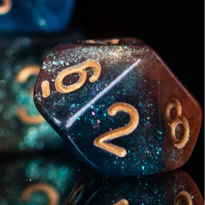 A set of acrylic dice featuring a mix of shimmering blue and orange colors with gold simple numbering for playing tabletop games and board games