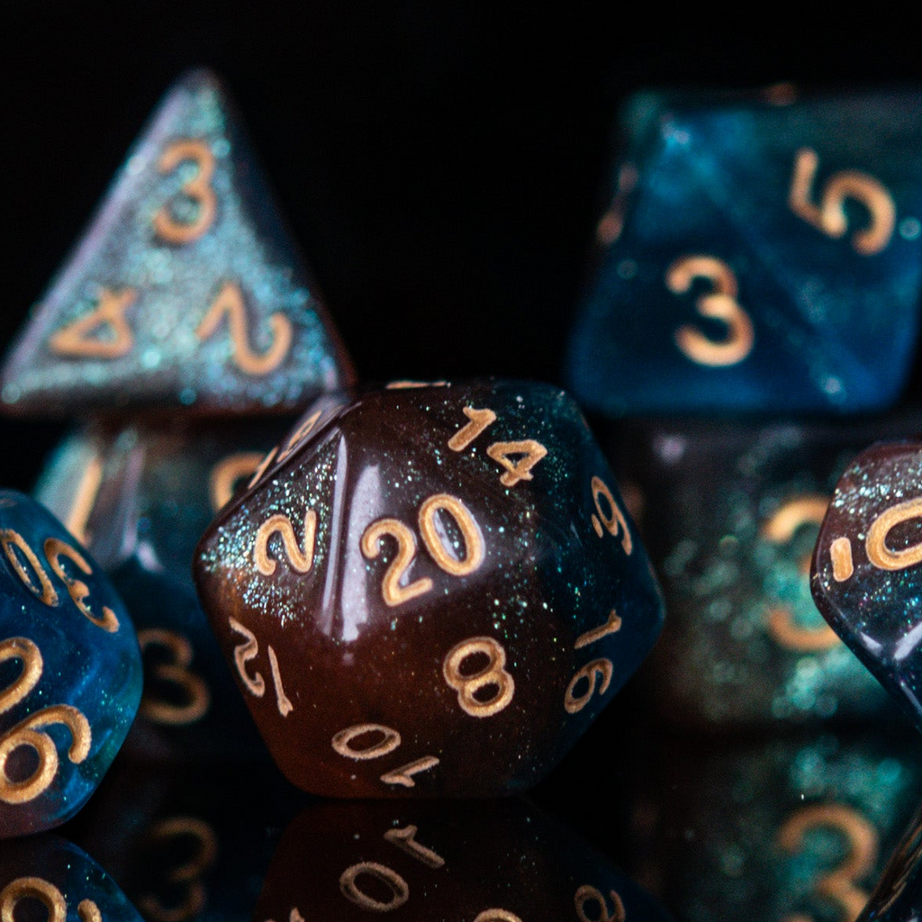 A set of acrylic dice featuring a mix of shimmering blue and orange colors with gold simple numbering for playing tabletop games and board games