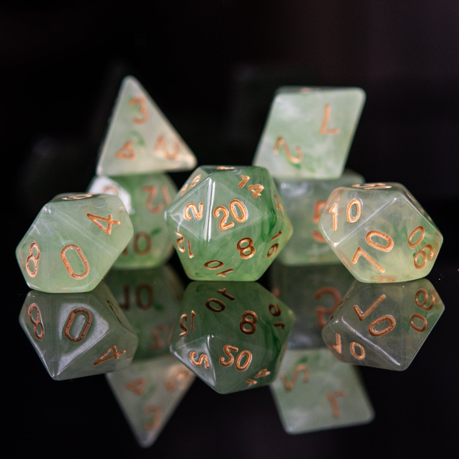 A set of translucent green acrylic dice with engraved numbers, displayed on a reflective surface.