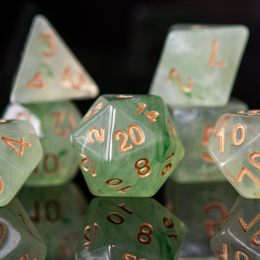 A set of translucent green acrylic dice with engraved numbers, displayed on a reflective surface.