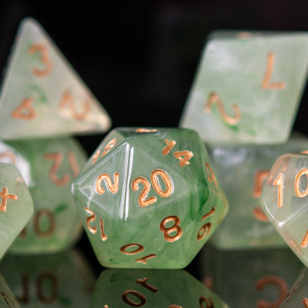 A set of translucent green acrylic dice with engraved numbers, displayed on a reflective surface.