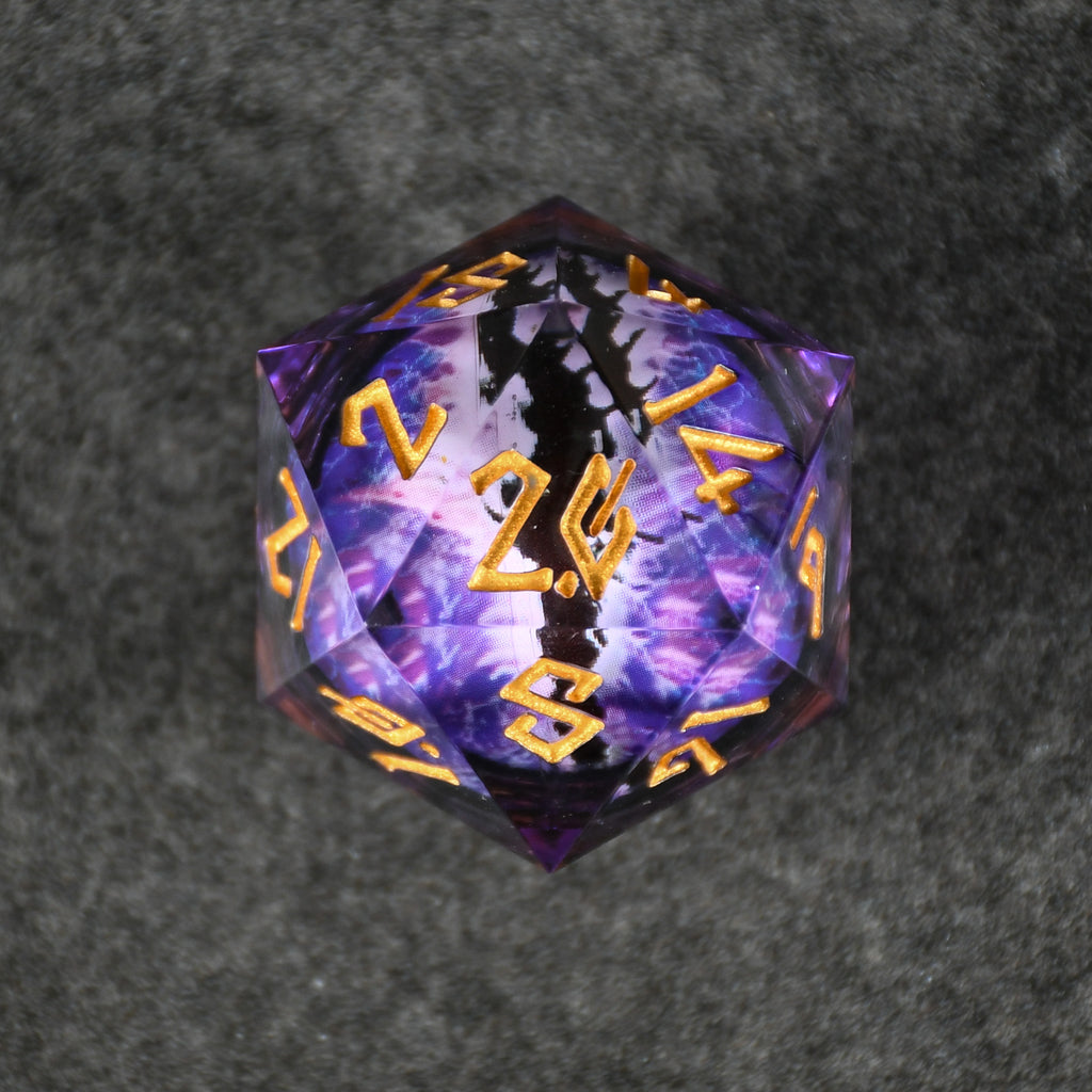 A 30mm clear oversized liquid core d20 dice with gold engraved numbers, featuring a floating purple dragons eye inside. 