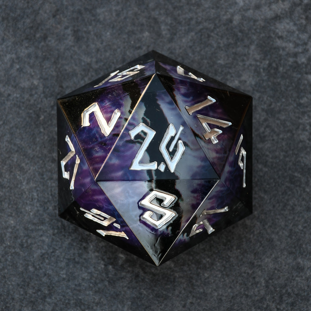 A 30mm black and silver oversized liquid core resin d20 dice with engraved numbers and a floating purple dragons eye design inside.