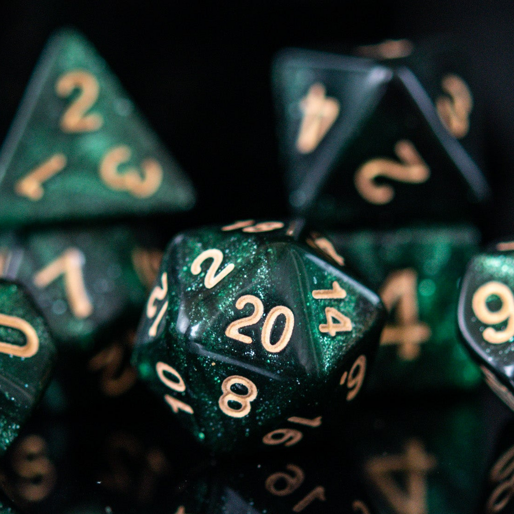 A set of shimmering deep green acrylic dice with engraved gold numbers, displayed on a reflective surface.