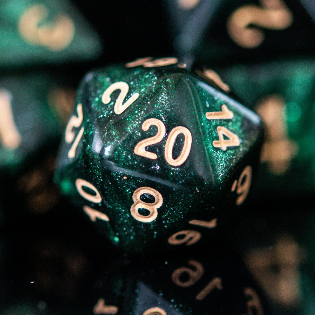 A set of shimmering deep green acrylic dice with engraved gold numbers, displayed on a reflective surface.