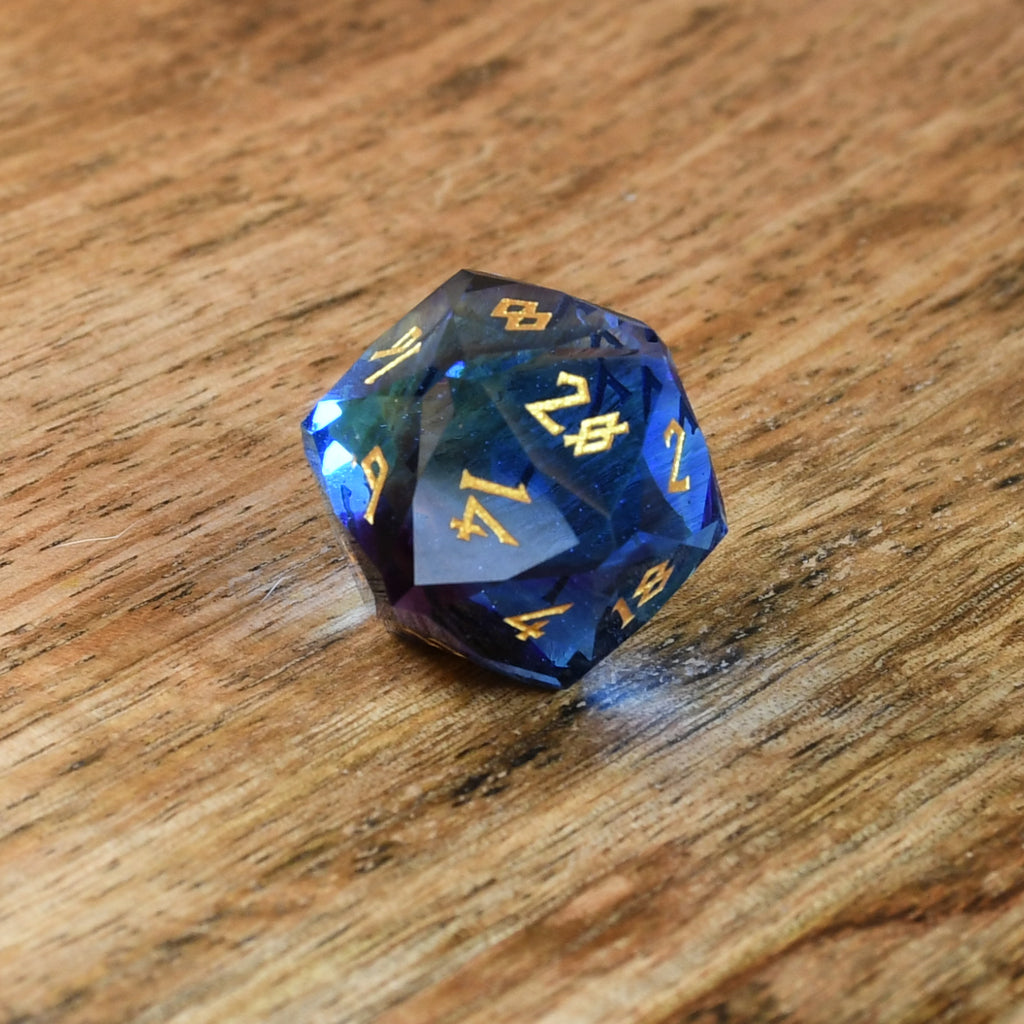 A set of multifaceted blue glass dice with engraved numbers, displayed on a wooden surface.