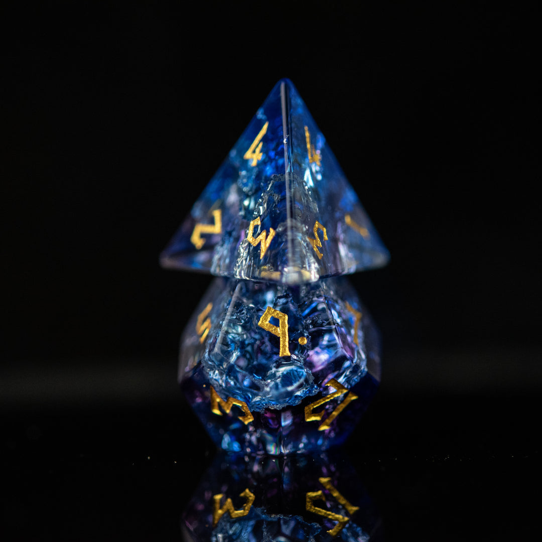 A set of hand-carved, multicolored glass dnd dice with engraved numbers, displaying a shattered glass effect.
