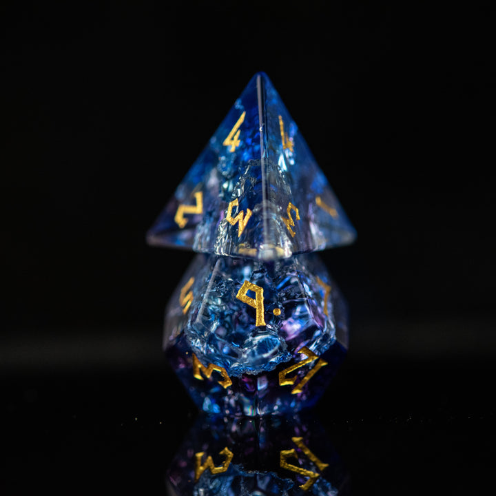 A set of hand-carved, multicolored glass dnd dice with engraved numbers, displaying a shattered glass effect.