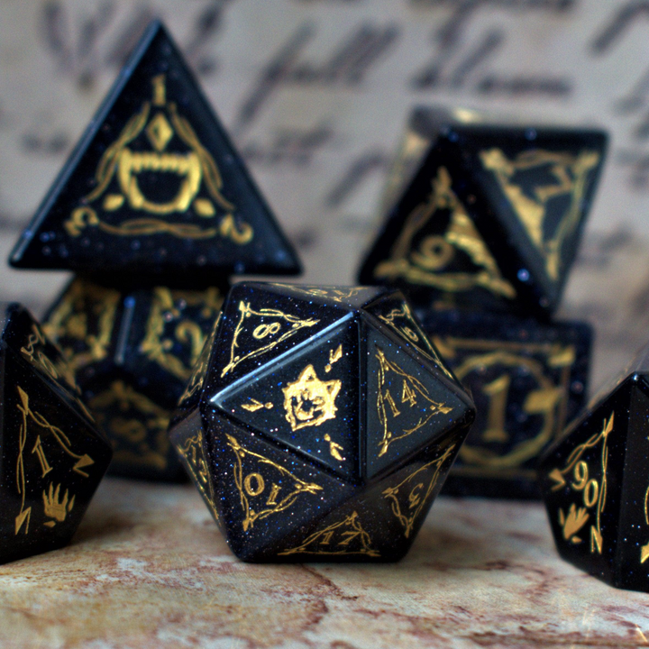 A set of Fangs of Winter Blue Sandstone Stone Dice with gold engravings on a textured background.