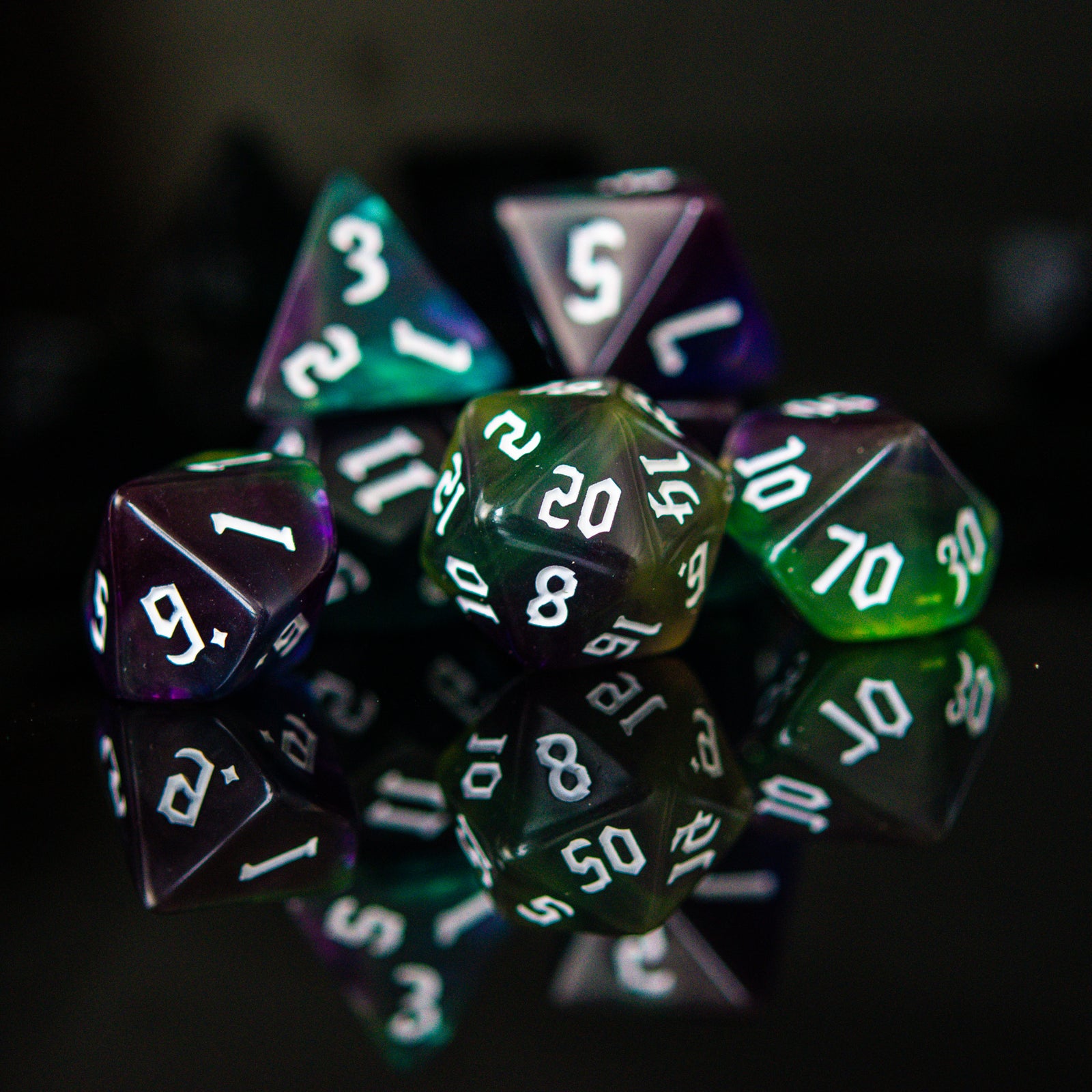 A set of multicolored acrylic dice with engraved numbers, displayed on a reflective surface.