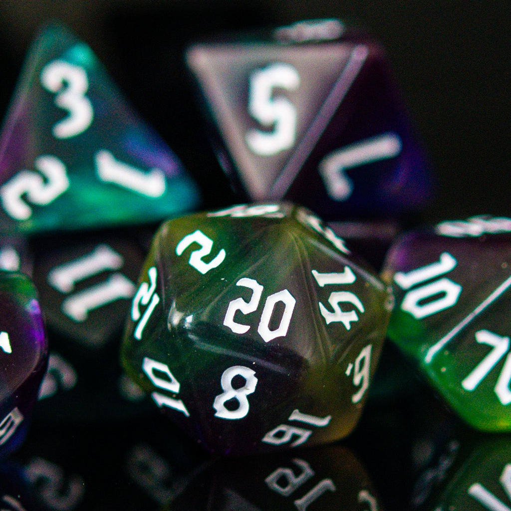 A set of multicolored acrylic dice with engraved numbers, displayed on a reflective surface.